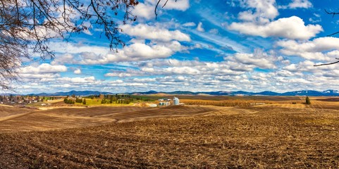 Farm land of rolling hills and grain silo in the distance