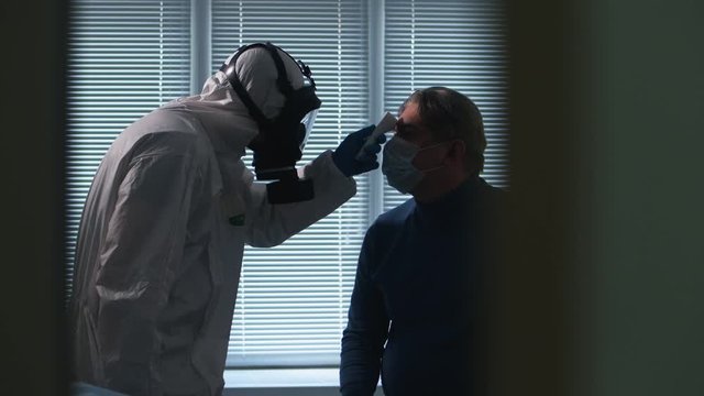 Paramedic is checking man's temperature with a modern device