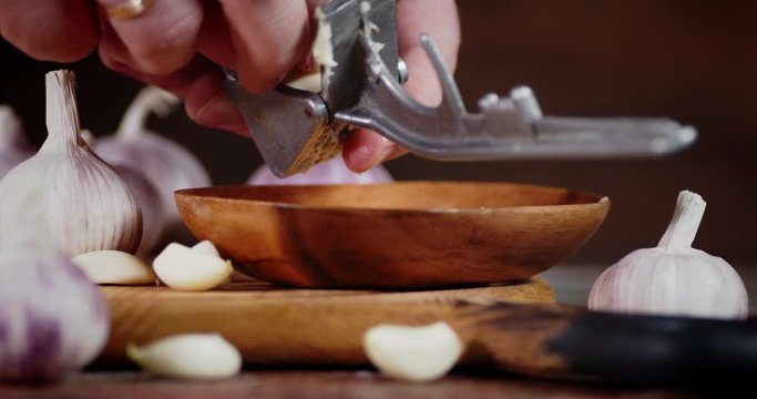 A man puts a garlic masher and presses it on a plate.