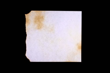 Obraz premium sheet of old paper with multiple damage from fire and time, isolated on black