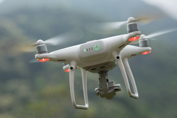 Naklejka na ściany i meble White drone with camera flying in spring mountains