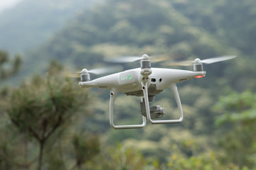 White drone with camera flying in tropical forest