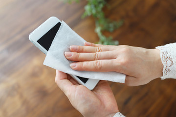 スマートフォンの画面を消毒する女性