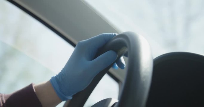 Hands in gloves on steering wheel driving car covid 19 pandemic crisis