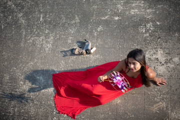 An young and attractive Indian brunette woman in red western dress enjoying with a pinwheel on the rooftop in a morning. Indian lifestyle and quarantine.