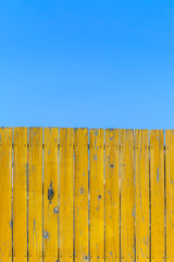 Fototapeta premium 青空と黄色の古びた板塀。背景用素材