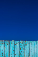 青空と青色の古びた板塀。背景用素材