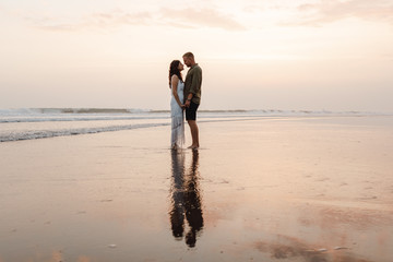 Romantic couple kissing on the beach. Couple in love having romantic tender moments at sunset on the beach