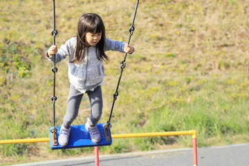 ブランコで立ちこぎをする幼児(5歳児)