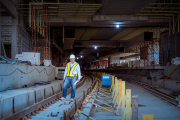 A senior engineer under inspection and checking construction process railway and checking work on railroad station platform .Engineer wearing safety uniform and safety helmet in work.