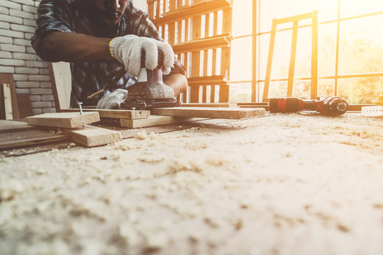 Carpenter working on wood craft at workshop to produce construction material or wooden furniture. The young Asian carpenter use professional tools for crafting. DIY maker and carpentry work concept.