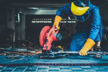 Professional mechanic is cutting steel metal with rotating diamond blade cutter. Steel industry and...