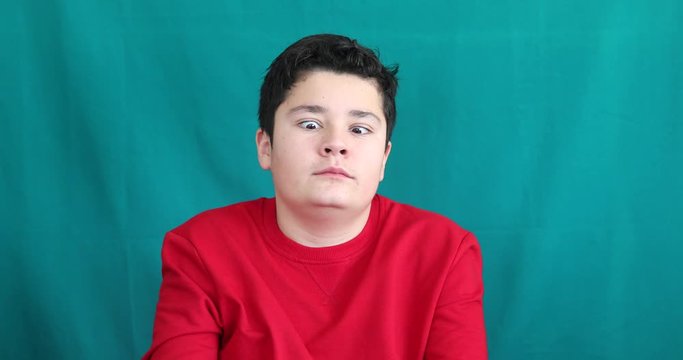 Portrait of a happy teenage boy making funny grimace gainst chroma key green screen background
