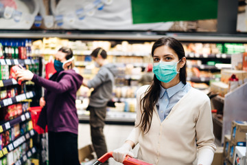 Shopper with mask safely buying for groceries due to coronavirus pandemic in grocery store.COVID-19 shopping.Quarantine preparation.Panic buying and stockpiling.Lockdown.Safety measures in supermarket