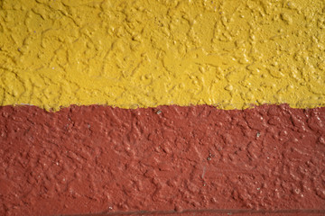 The yellow and orange or red wall made of concrete.