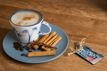 Cup of coffee with cinnamon sticks on a wooden table