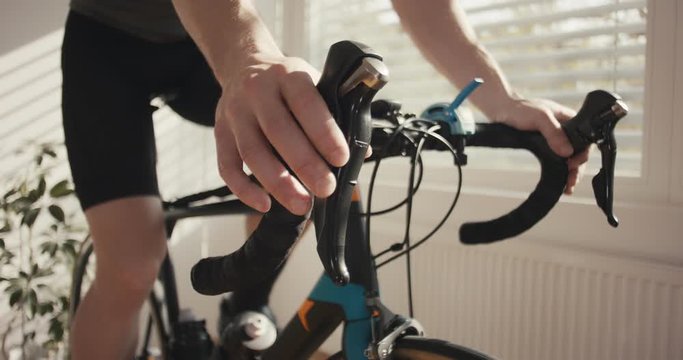 Man spinning home bicycle trainer training for wellbeing during virus outbreak unrecognizable gears lever detail