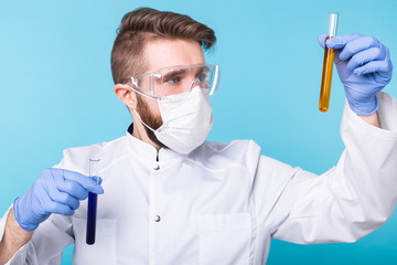 Covid-19, coronavirus, Vaccine development, pandemic, outbreak and medicine concept - Man scientist in flu mask and protective gloves holding a test tube.