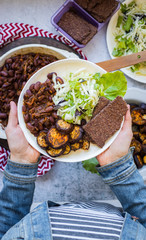 Vegan mixed vegetables lunch on plate. Beans, eggplants, cabbage salad, flatbreads. Vegetarian food dinner. Woman hands