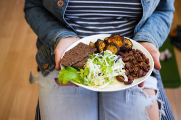 Vegan mixed vegetables lunch on plate. Beans, eggplants, cabbage salad, flatbreads. Vegetarian food dinner. Woman hands