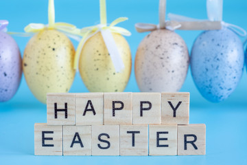 Happy Easter text made of wooden letters on a turquoise background