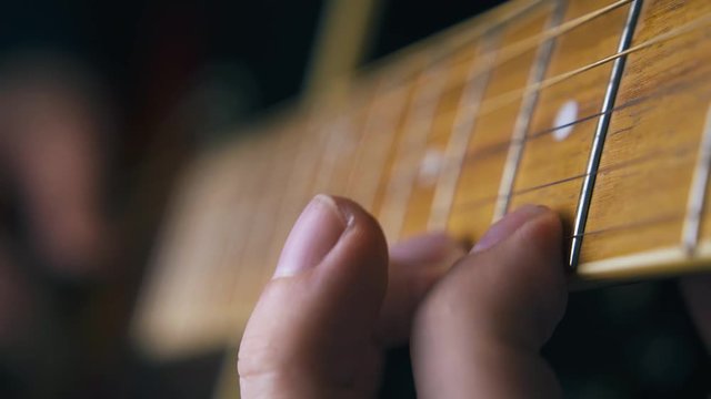 CU: skilled musician plays acoustic guitar nylon strings striking chords on brown fretboard extreme close view