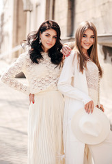 beautiful girls with dark hair in elegant clothes posing in the street