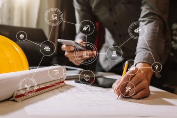 business man hand working and laptop with on on architectural project at construction site at office desk in office