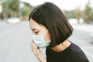 Asian woman suffer from cough with face mask protection,woman wearing face mask because of air pollution in the city building,Sick woman with medical mask;concept of pollution,dust allergies