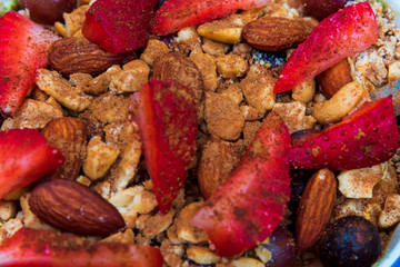 A smoothie bowl with oats, almond milk, almond yogurt, spinach, banana, berries, sliced strawberries, grapes topped with crushed almonds, almonds, Ezekiel cereal and a splash of cinnamon 