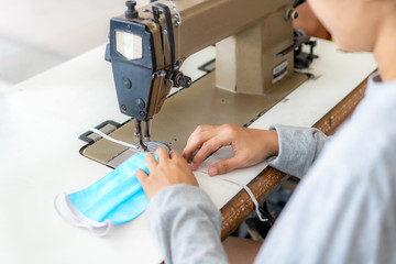 Woman hands using the sewing machine to sew the face medical mask during the coronavirus pandemia. Home made diy protective mask against virus.