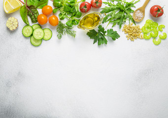 Fototapeta na wymiar Raw fresh ingredients for vegetarian salad:cherry tomatoes,arugula leaves,parsley,cucumber,lemon,garlic,olive oil,celery and sea salt on light background.