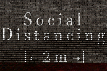 social distancing painted on a brick wall