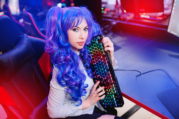 Girl gamer with keyboard and headphones playing online games on computer
