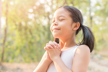 Fototapeta premium cute little girl hands praying to god with the bible in the morning on nature background. little asian girl hand praying for thank god. copy space. spirituality and religion faith hope concept.