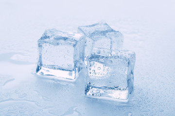 Obraz premium several melted ice cubes with drops on a light background with blue tinting