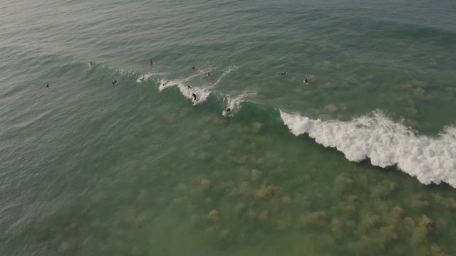 Drone View Of Surfers Paddling Back Behind The Waves At Line Up, Top Down Arial Shot Of Surfers On Waves