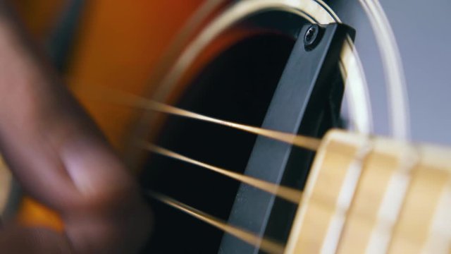 CU: skilled guitarist plays brown acoustic guitar with black pickups and practices various techniques extreme close view