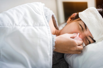 Fototapeta na wymiar Sick asian woman have hight fever flu and sneezing into tissue on bed in bedroom, Healthcare and prevent the spread infection corona virus concept, Selective focus.