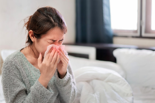 Sick asian woman have hight fever flu and sneezing into tissue on bed in bedroom, Healthcare and prevent the spread infection corona virus concept, Selective focus.