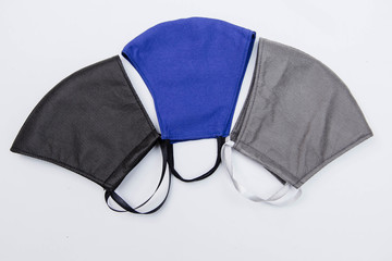 Close-up of three handmade medical masks of different colors, black, blue and gray isolated on a white background. The concept of scarcity of medical masks and the popularization of handmade masks.