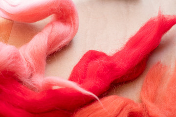 Background with wool for felting red color lying on a wooden table