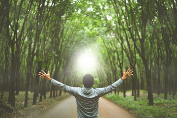 Man raise hand up in forrest with sunlight ray abstract background. Freedom feel good and trave...