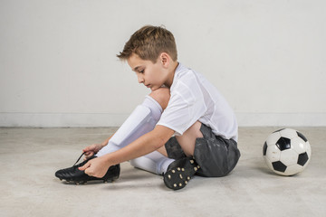 young soccer boy player putting on his cleats - Powered by Adobe