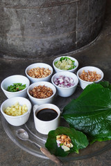 Miang kham is a popular street food in many parts of Thailand and the vendor places above six ingredients in the leaf with a dollop of sauce, and then wraps up the bundle and skewers it onto a stick.