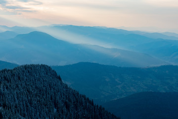 the rays of the sun pass through the clouds at sunset on the mountain