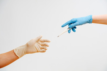 close-up hands of people in gloves pass a thermometer