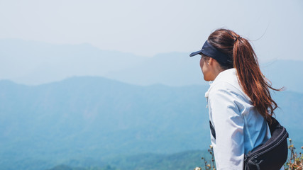 A woman hiking and standing on the top of mountains looking at a beautiful view