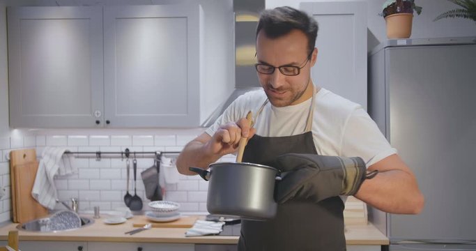 Attractive young man cooking food in nice kitchen for dinner