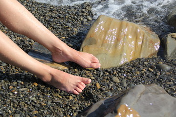 Two women's feet on a shingle beach by the sea